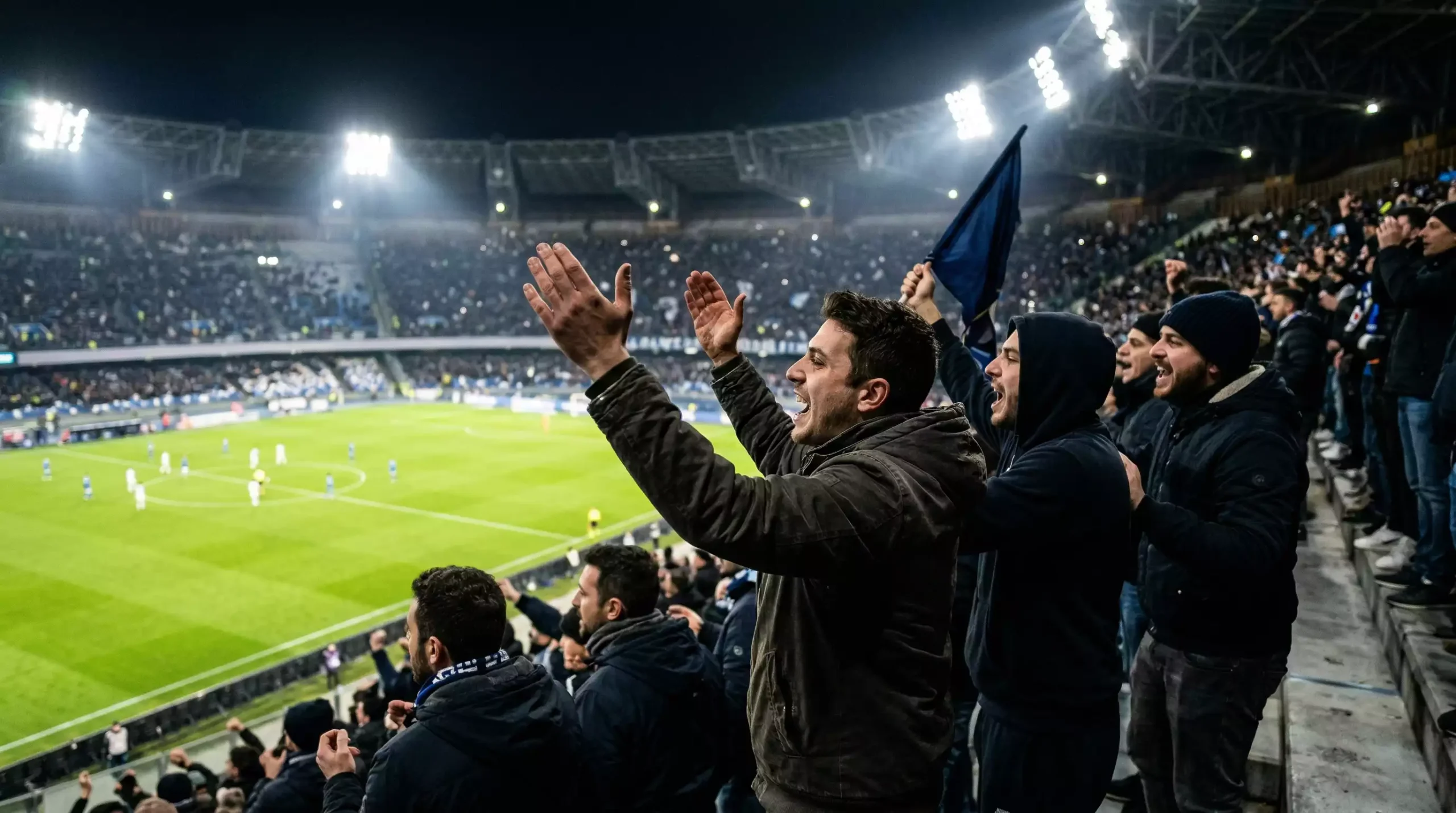 Tifosi che guardano una partita di calcio in uno stadio illuminato